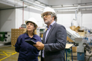 Supervisor falando com uma trabalhadora da fábrica e segurando um tablet